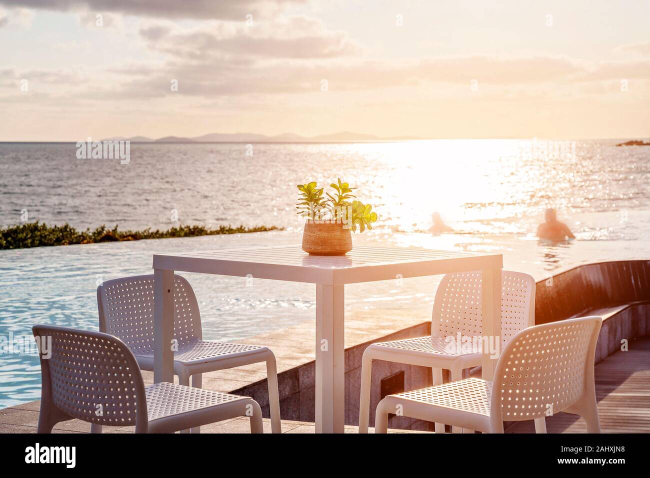 Tisch und Stühlen neben einem Infinity Edge Lagune in sanften Morgenlicht aus über dem Ozean umspült, ein friedlicher Vista in Australien. Schwimmen Stockfoto