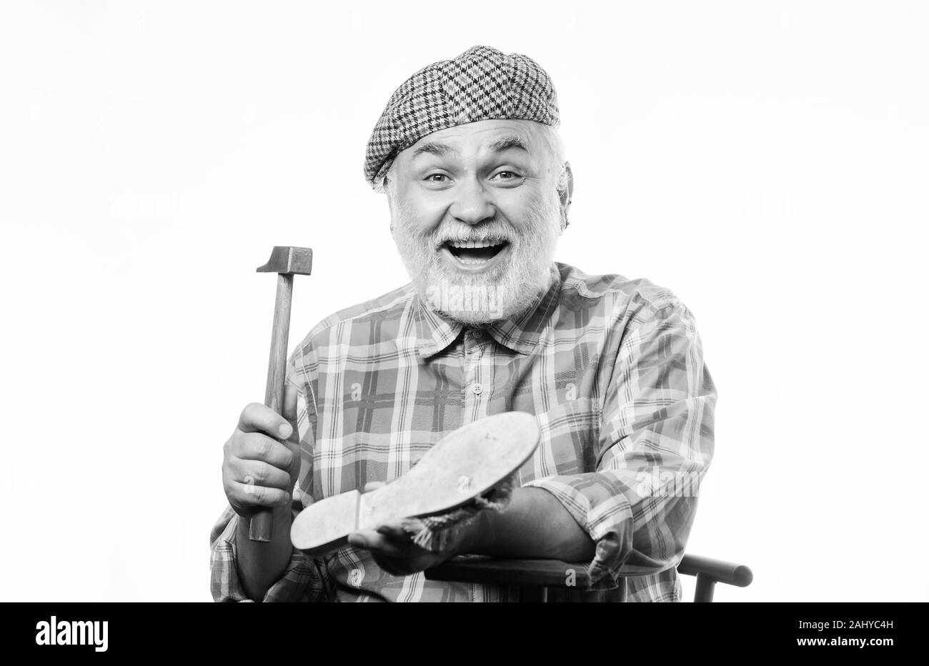 Retro mann Reparatur Schuhe mit Hammer. reife Schuster in der Werkstatt Schuhe machen. Schuster arbeiten mit Leder Textil- und Hammer. Schuster Verarbeitung. Schuster bei der Arbeit. Jedes Detail muss perfekt sein. Stockfoto