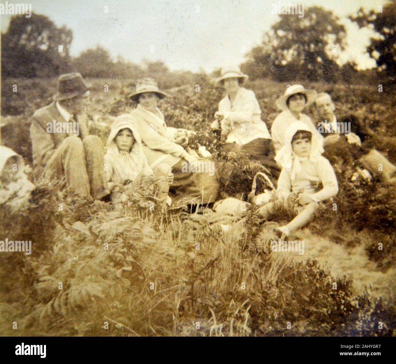 Alte vintage schwarz-weiß Foto von einer Gruppe von Menschen saßen in einem Feld in der Landschaft Stockfoto