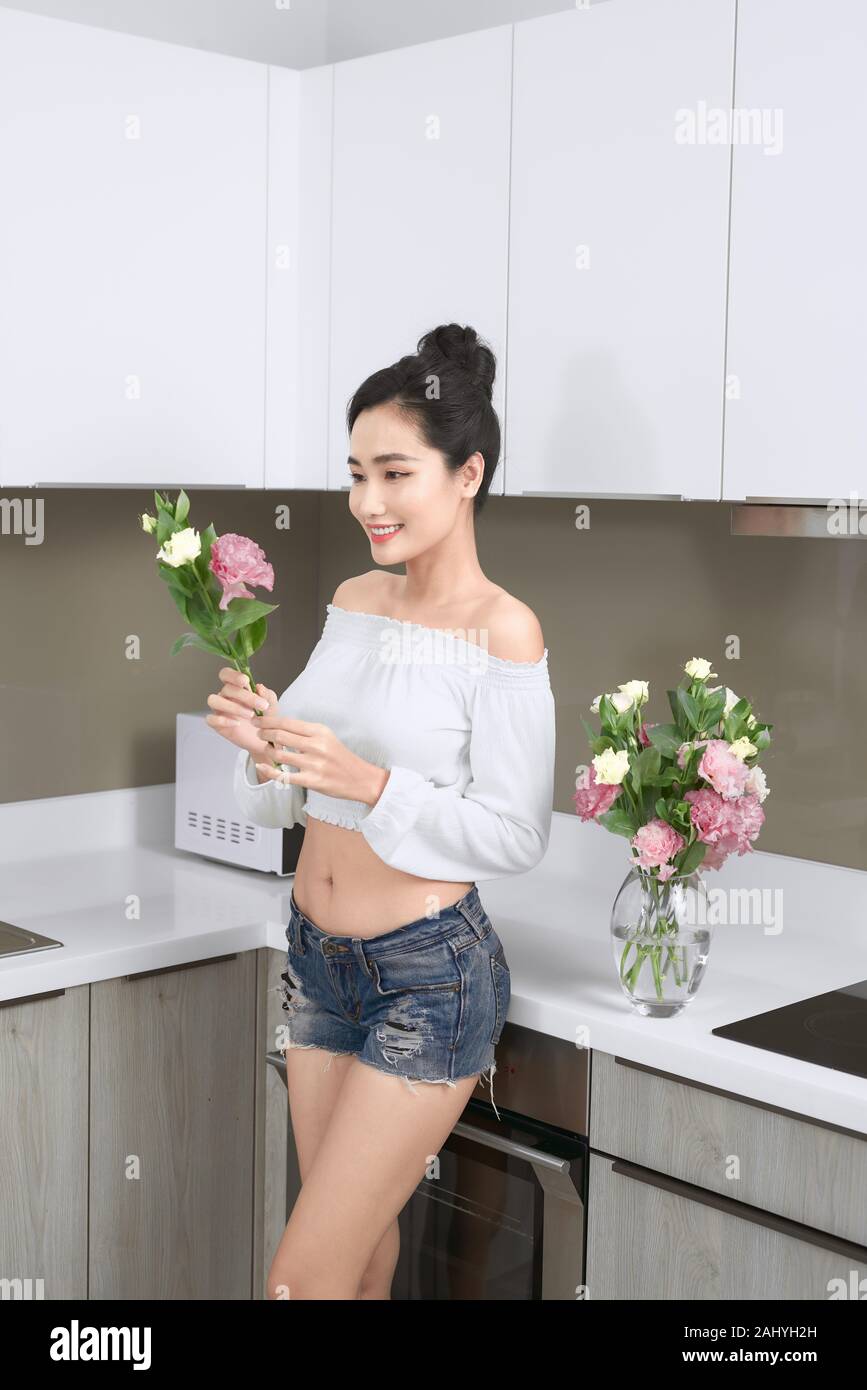 Junge asiatische Frau Anordnen von Blumen in der Küche. Stockfoto
