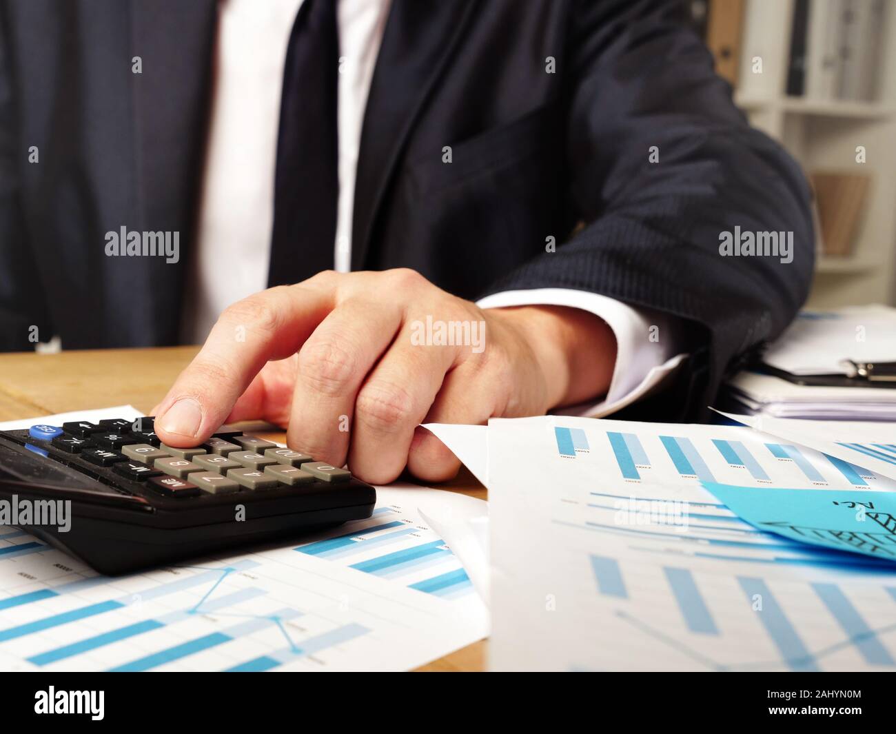 Der Mensch ist die Berechnung der Geschäftsbericht mit Taschenrechner und Stapel von Papier. Stockfoto