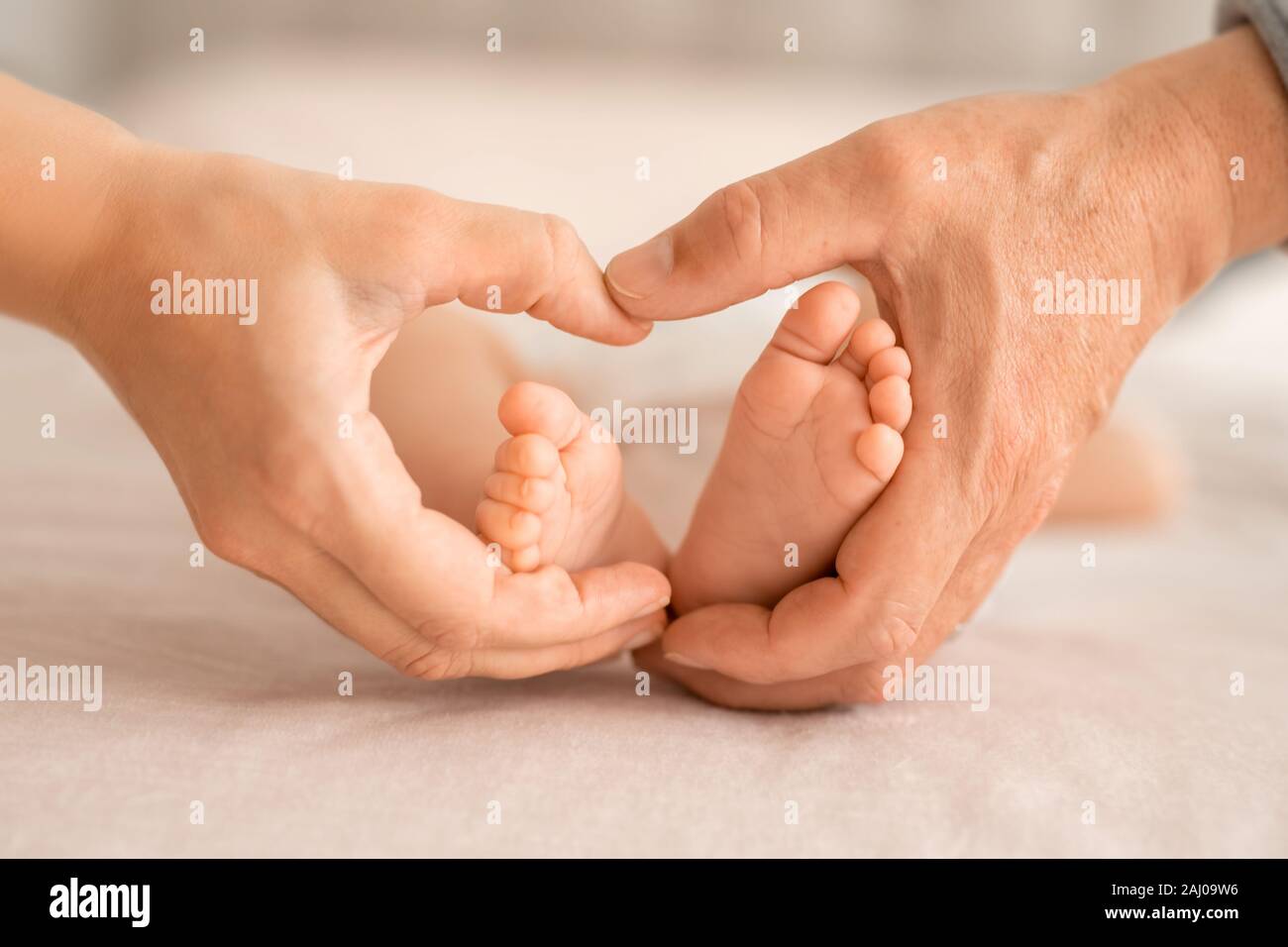 Ein kleines Baby Füße in Mutter und Vater Palmen in Form eines Herzens Stockfoto