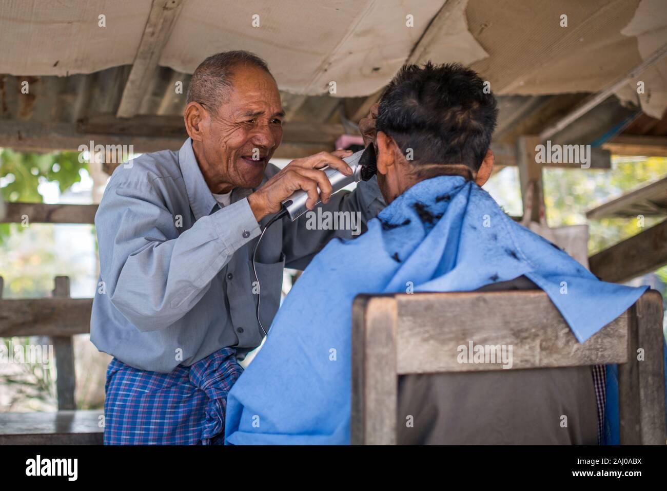 Mandalay, Myanmar - Januar 11, 2016: Ein unbekannter Mann Haare schneiden für den Kunden in einem Friseur. Stockfoto