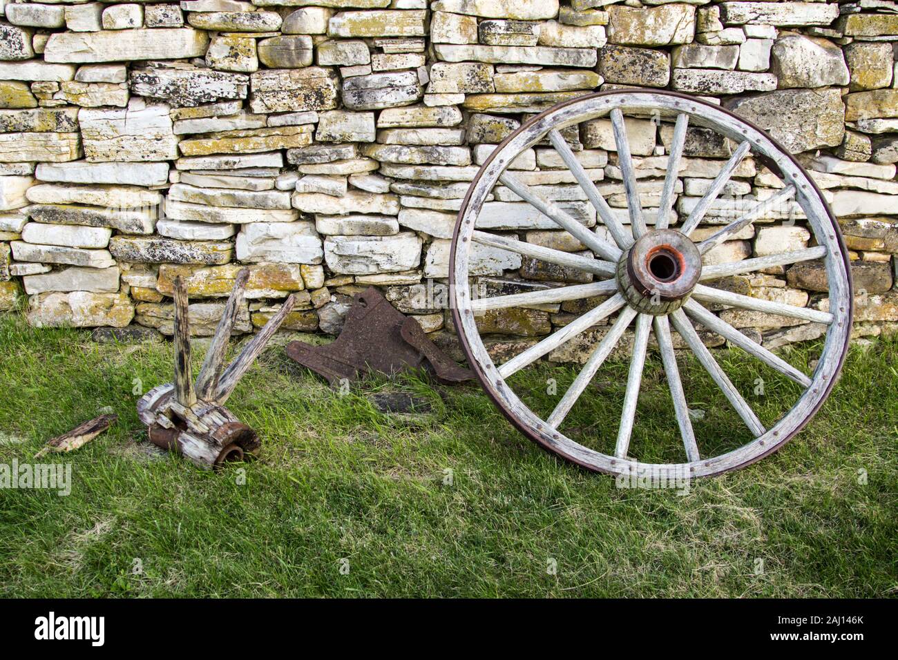 Wagon Wheel. Hölzernen Wagen Rad gegen eine alte Stein Wand lehnt. Stockfoto