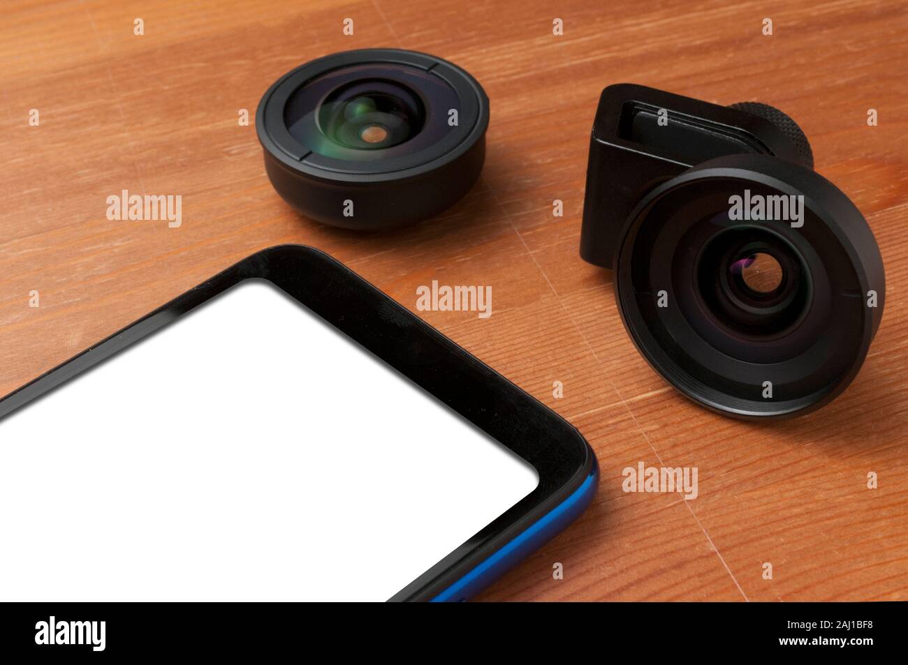 Leerer Bildschirm Smartphone auf Holztisch mit einigen Add-on Linsen Stockfoto