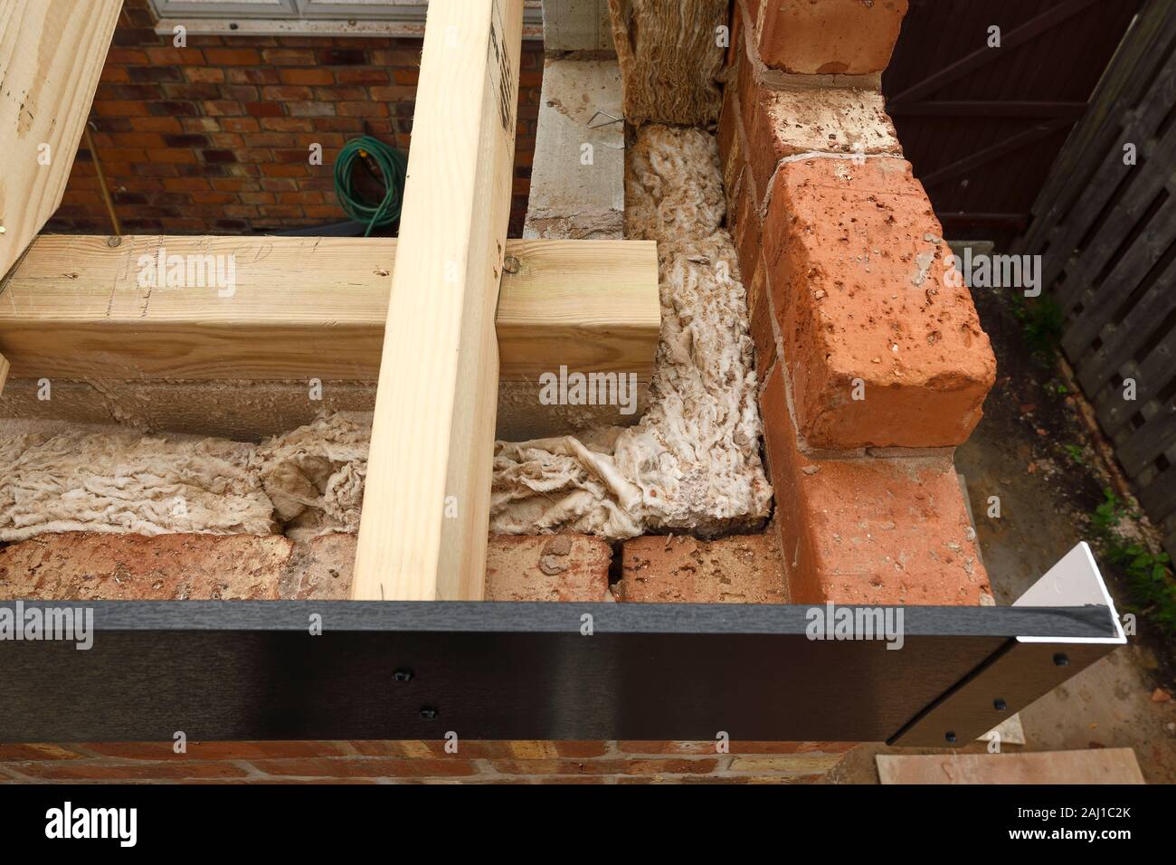 Nahaufnahme Detail einer zweischaligen Wand mit einem UK Baustelle zeigt die mineralische Wand Isolierung und Wandhalter für das Holzdach Struktur Stockfoto