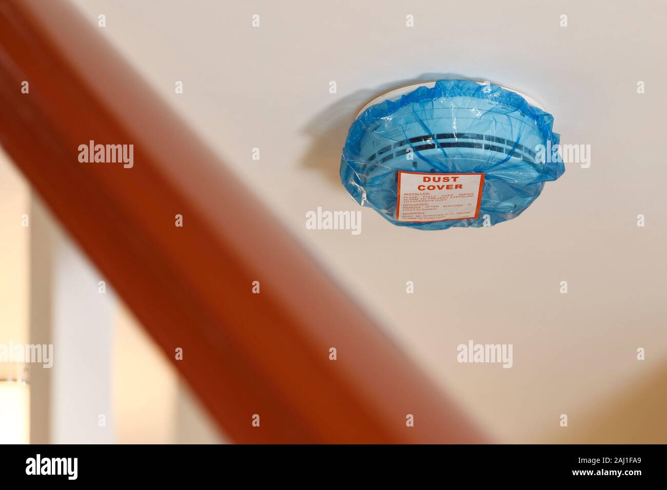Eine blaue Plastiktüte Staubabdeckung auf ein Netz verdrahtet Rauchmelder in einer BRITISCHEN inländischen Eigenschaft ausgestattet Stockfoto
