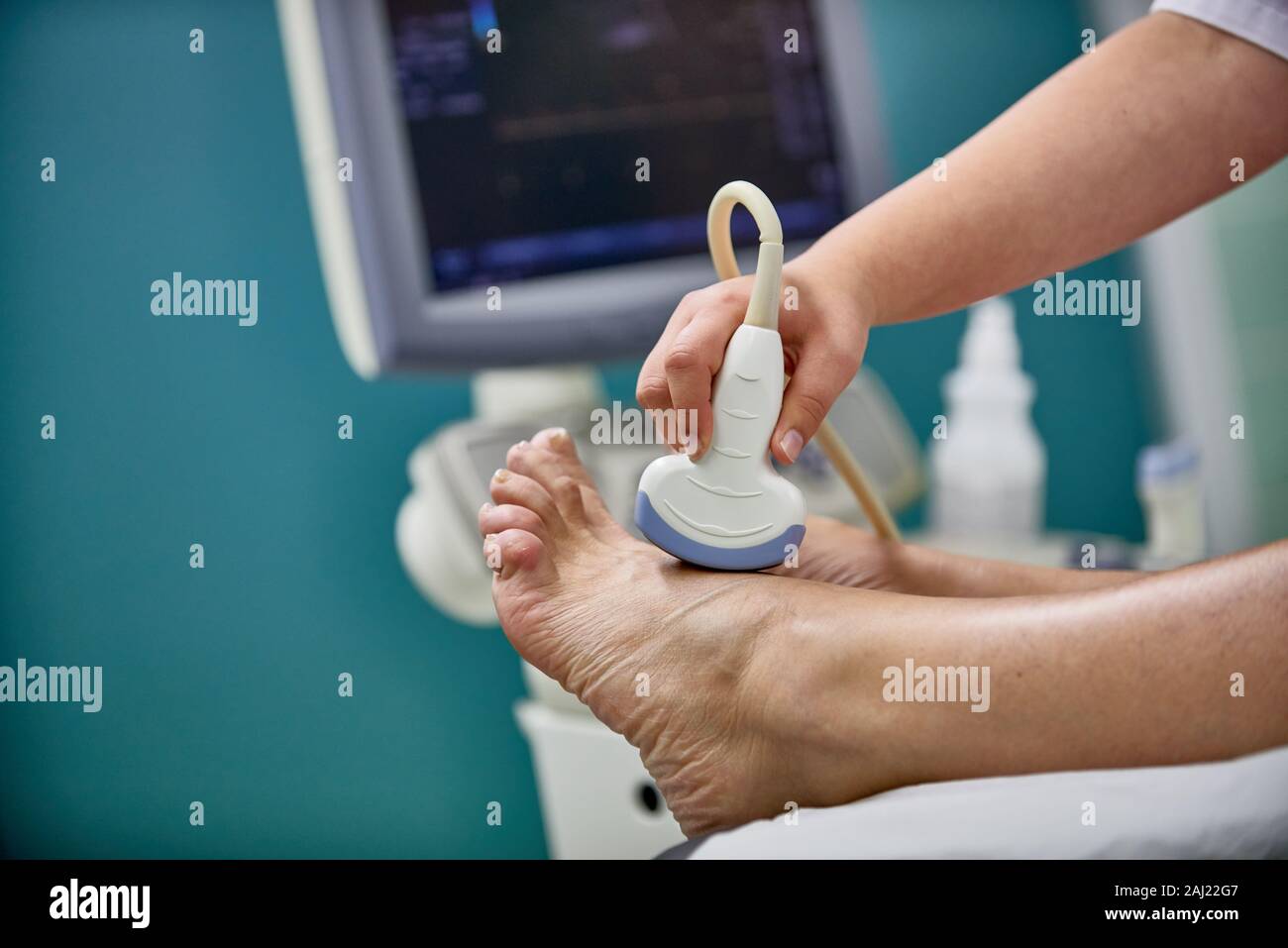 Arzt mit dem Ultraschall Gerät in einer Hand checkst Fuß des Patienten Stockfoto