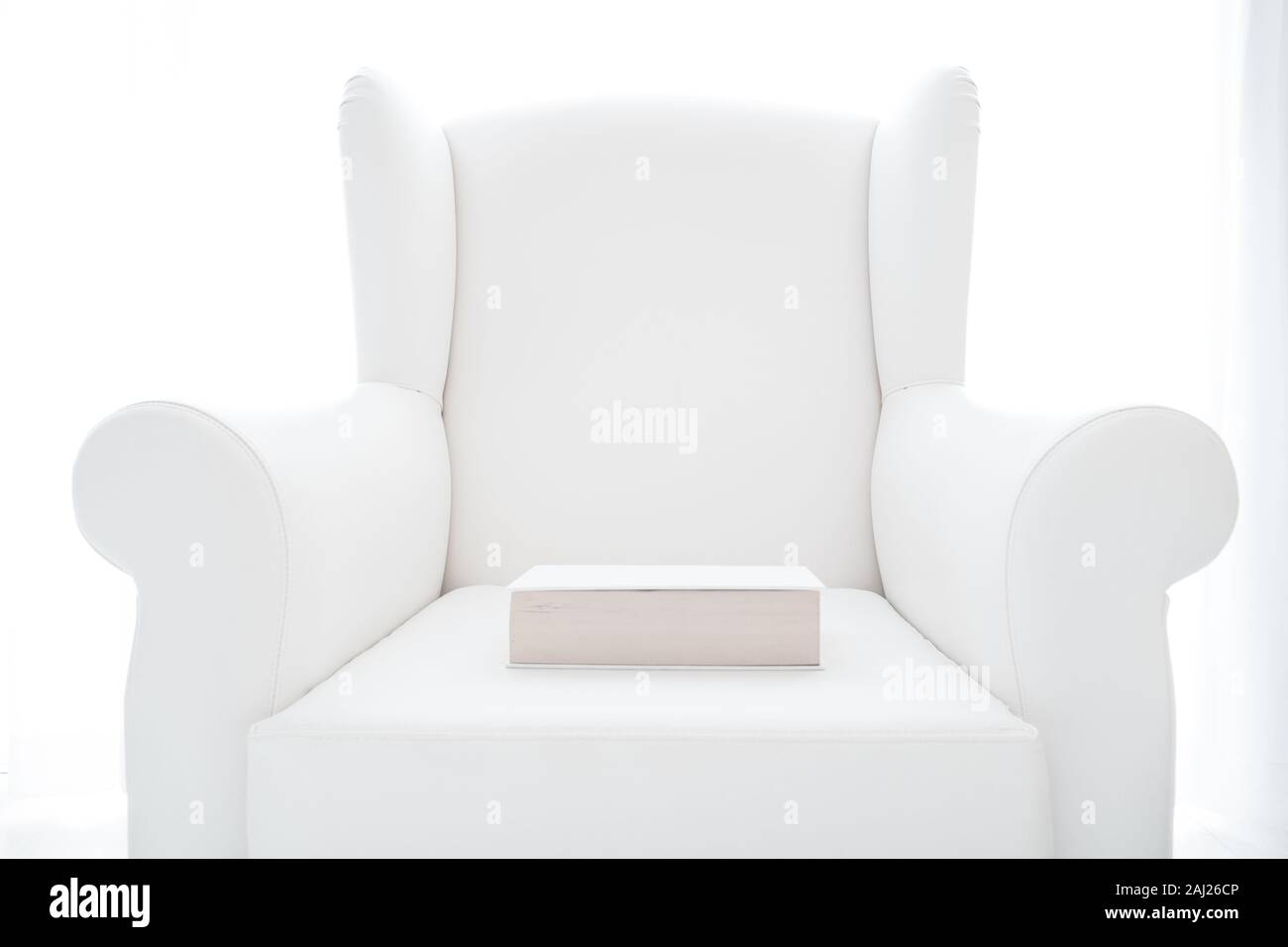 Weiß-Foto von einem Hardcover Buch auf einem weissen Sessel im Innenbereich Stockfoto