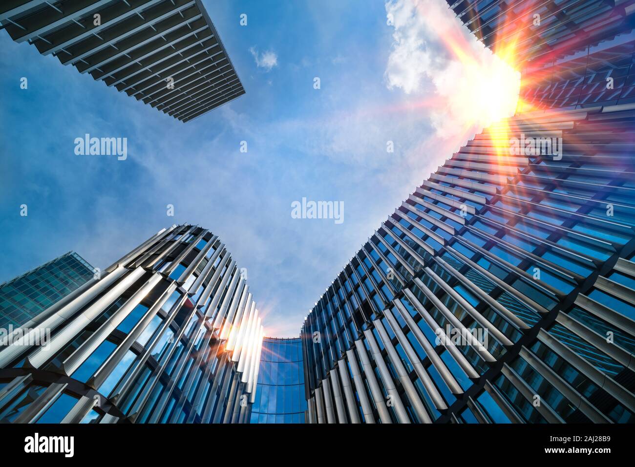 Modernes hohes Gebäude, Ansicht von unten. Sonne am blauen Himmel. Oberen Teil der Wolkenkratzer im Stadtzentrum. Sonnenstrahlen spiegeln auf der Fassade. Metropole detail. Stockfoto