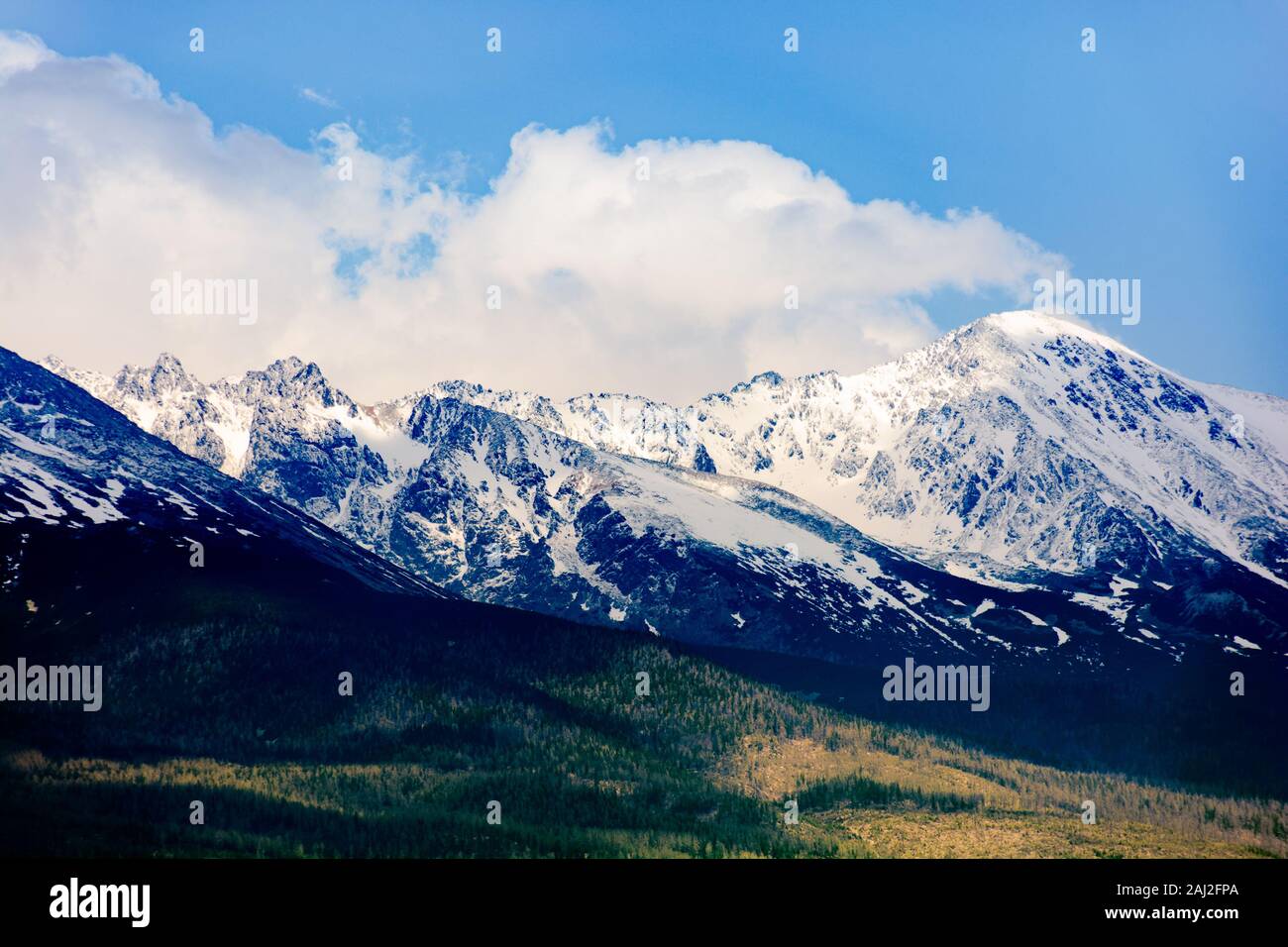 Hohe Tatra Bergkamm im Frühling. Schnee felsigen Gipfeln in dramatischen dappled Sonnenlicht unter einem Wolken am blauen Himmel bedeckte. Ort der Erde erfüllt. Stockfoto