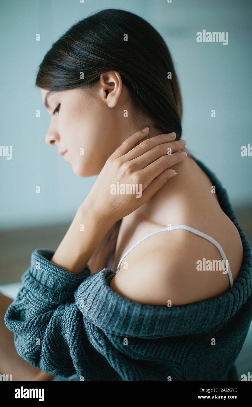 Nahaufnahme eines brünette Frau Massing ihren Hals in einem Schlafzimmer Stockfoto