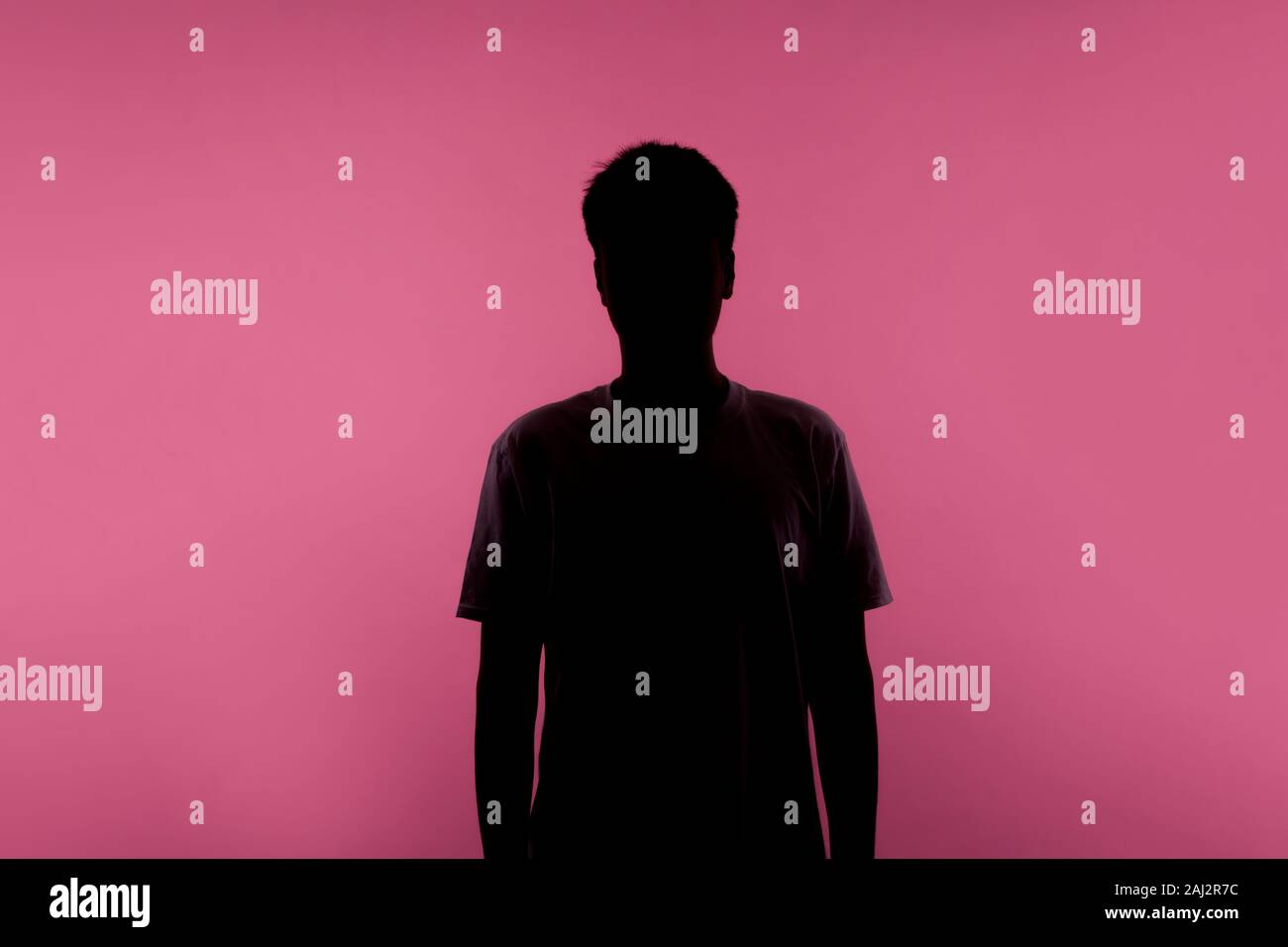 Kein Name, anonyme Person ausblenden Gesicht im Schatten, menschlichen Identität. Silhouette Porträt des jungen Mannes in Casual T-Shirt stand ruhig mit Hände unten, Ind Stockfoto