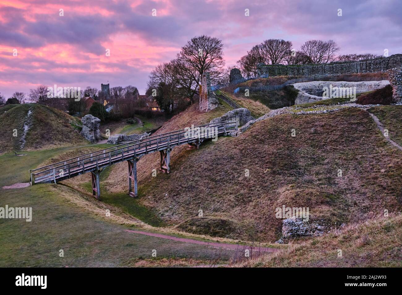 Dramatische lebendige Dezember Sonnenuntergang über dem 11. Jahrhundert von den Ruinen des Schlosses Acre Befestigungsanlagen in Norfolk, England Stockfoto