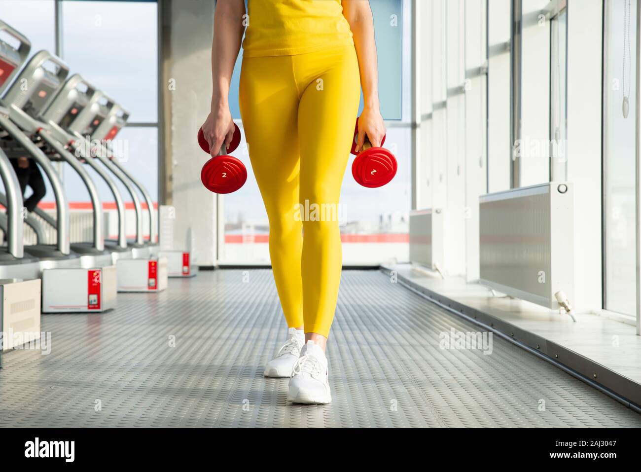 Körperlich fit Frau am Fitnessraum mit Hanteln bereit, ihre Arme und Bizeps zu stärken Stockfoto