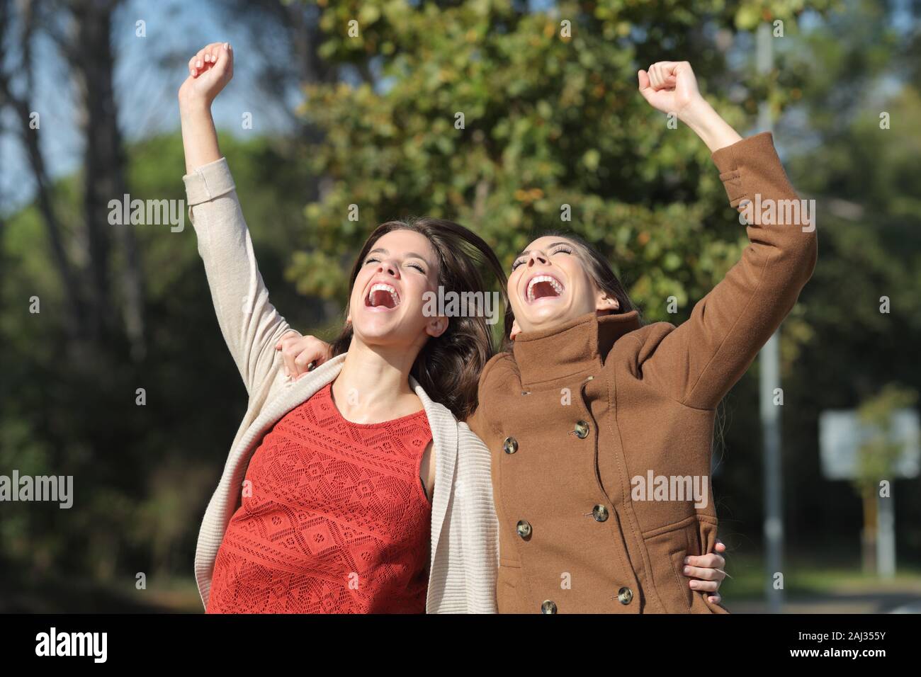 Zwei aufgeregt Frauen Erfolge feiern zusammen in einem Park springen im Winter Stockfoto
