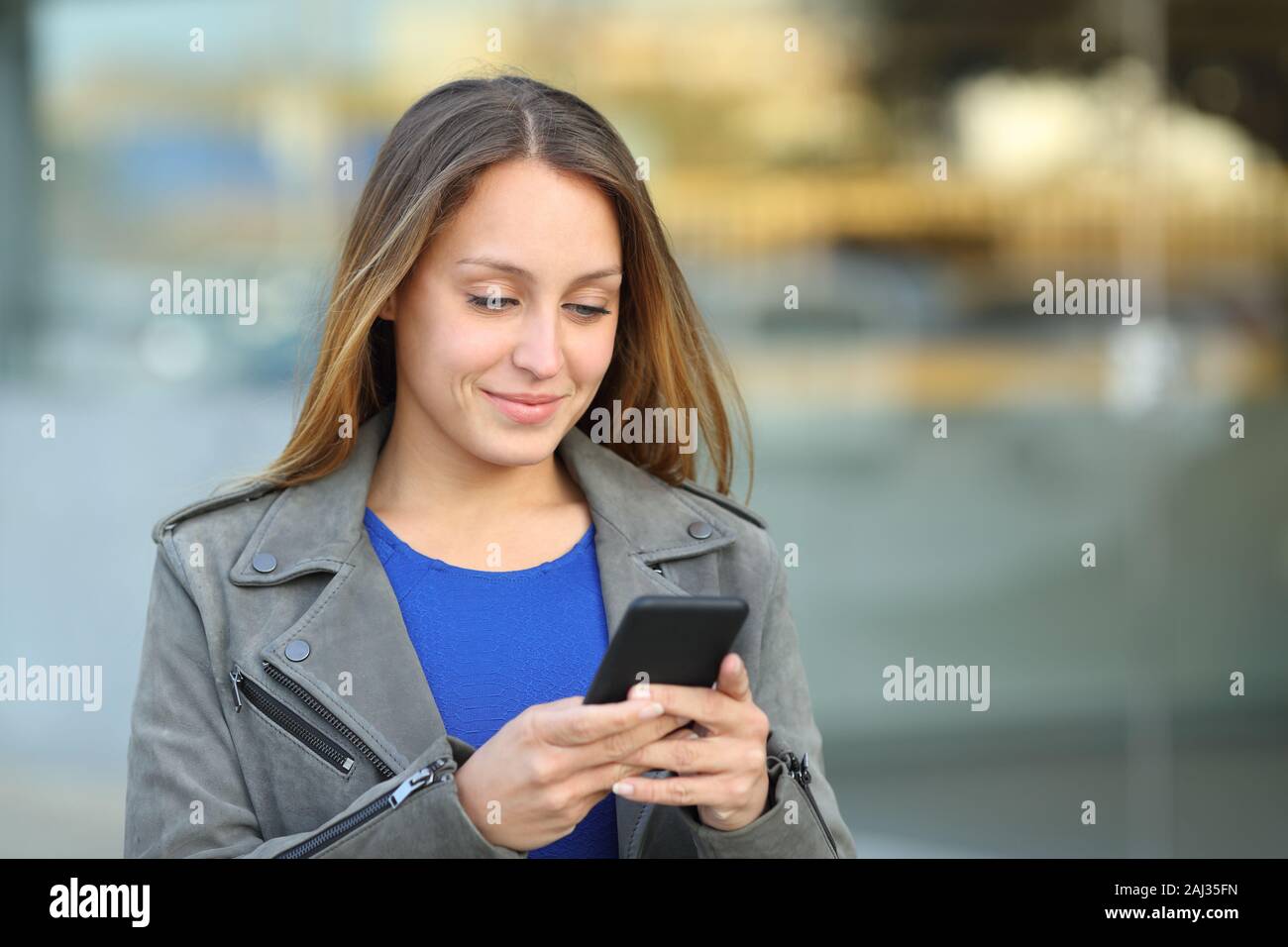 Informelle Besucherin über Handy zu Fuß auf der Straße Stockfoto