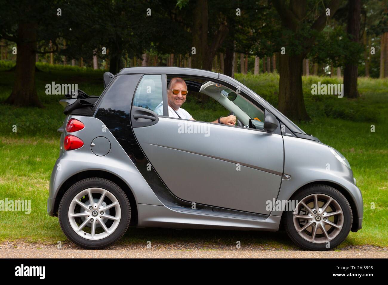 Lächelnd im mittleren Alter cool Mann in Smart Auto mit Verdeck Stockfoto