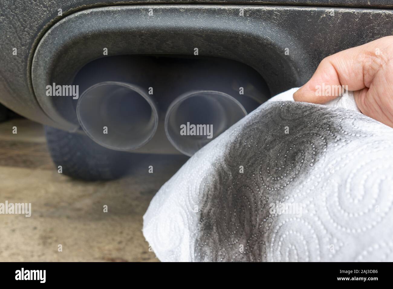 Hand mit einem schmutzigen weißen Tuch vor dem Rauchen Auspuff eines Autos mit Dieselmotor. Stockfoto