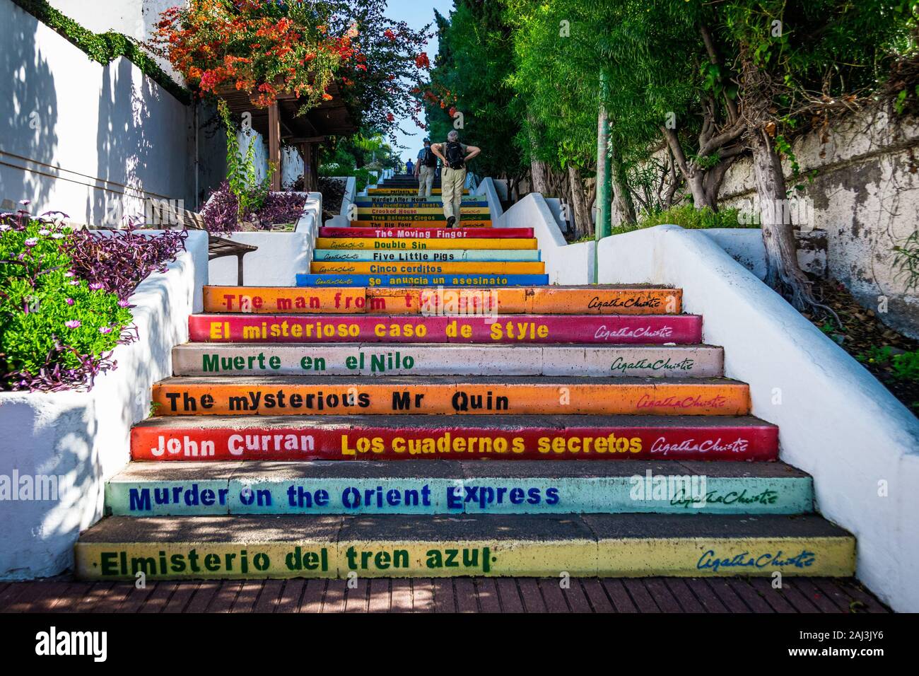 Ältere touristische Paar klettern bunte Treppe mit Buch von Agatha Christie Titel auf ihnen in Puerto de la Cruz, Teneriffa, Spanien geschrieben. Stockfoto