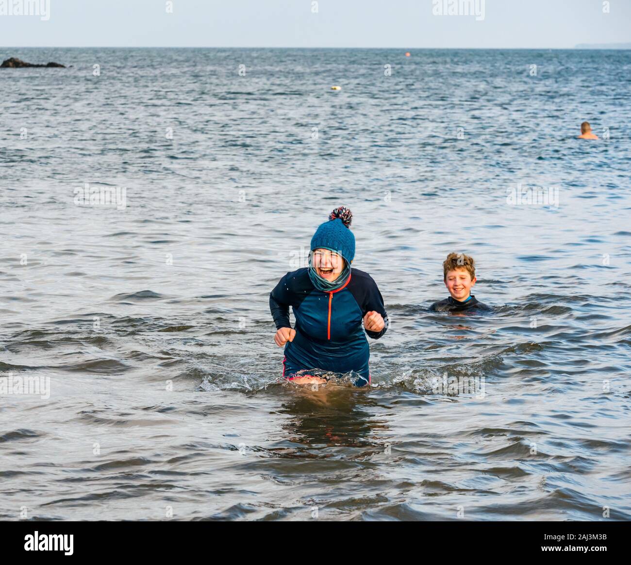 Die Menschen im Meer für 2020 das Neue Jahr Loony Dook oder Dip mit einer jungen Frau das Tragen eines Bobble hat Lachen, North Berwick, East Lothian, Schottland, Großbritannien Stockfoto