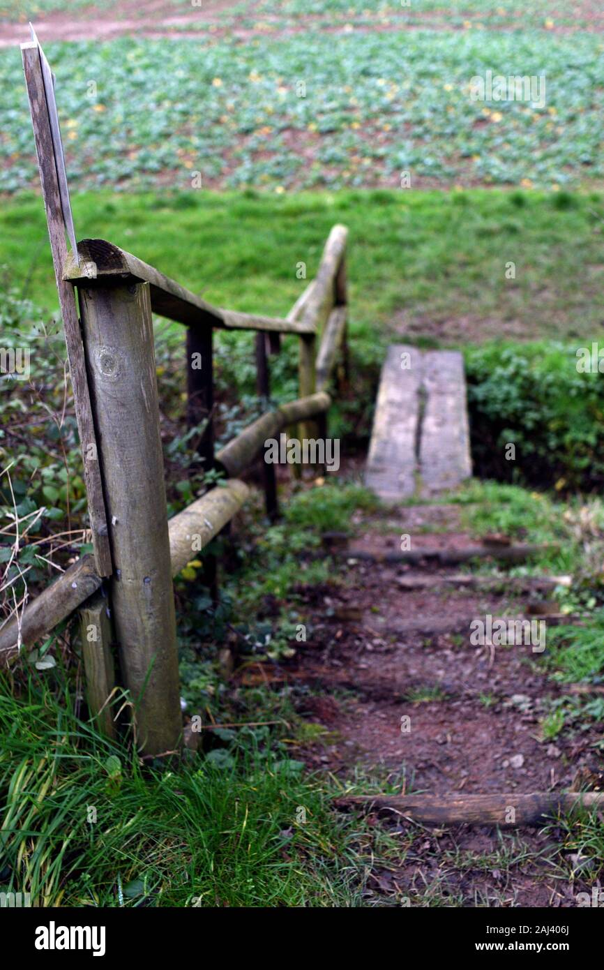 Kleinen hölzernen Brücke mit Geländer über Graben in Ackerland in England Stockfoto