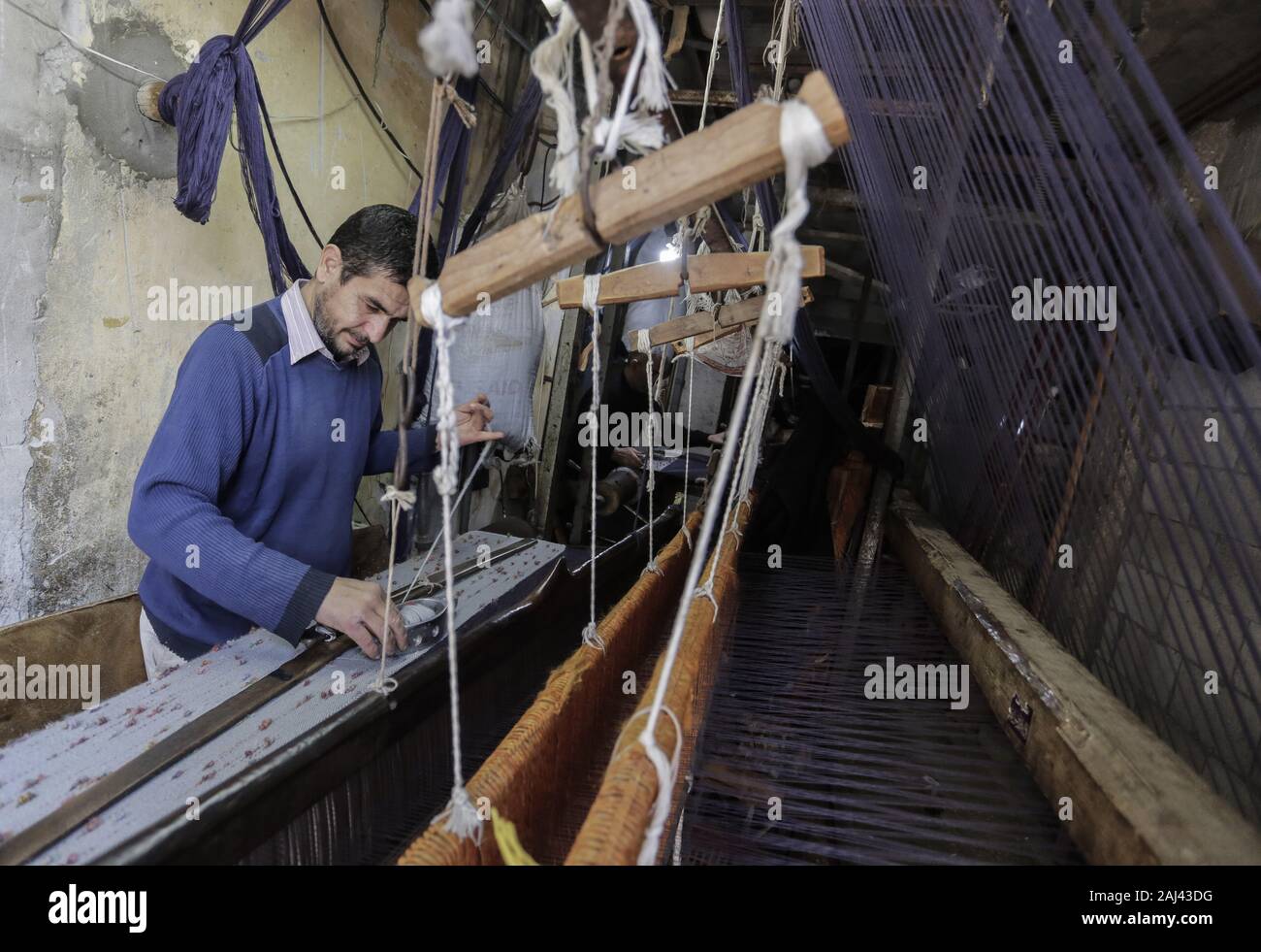 Gaza, Palästina. 2 Jan, 2020. Eine palästinensische Arbeiter webt Teppiche auf einem traditionellen Webstuhl an einem Teppich Fabrik in Gaza Stadt. Sprechen über alte Gaza, und was erscheint, sind die Bilder der Ton, bunte Glaswaren, Bambusmöbel und alten Rahmen Weben Webstühle helle Teppiche und Matten. Als solche Berufe sterben weltweit werden könnte, ist das Tempo ihrer sinkt zu schnell in Gaza, die sich aus der rund 500 Webstühlen, nur ein noch funktioniert. Credit: Mahmoud Issa/SOPA Images/ZUMA Draht/Alamy leben Nachrichten Stockfoto