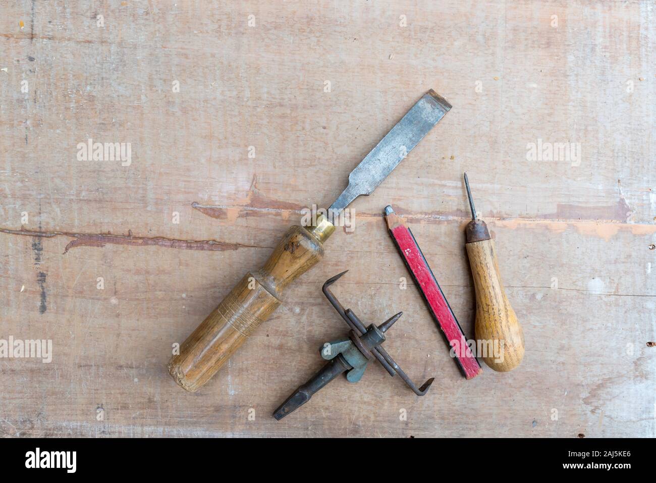 Eine alte Meißel und andererseits Werkzeuge flach auf eine raue Oberfläche Stück Holz mit Farbe Spuren und Kratzer Stockfoto