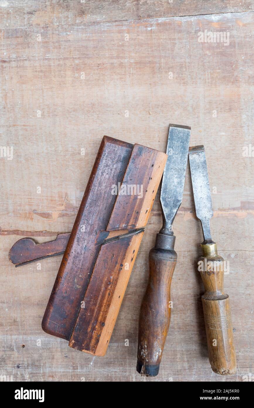 Alte Meißel und andererseits Werkzeuge flach auf eine raue Oberfläche Stück Holz mit Farbe Spuren und Kratzer Stockfoto