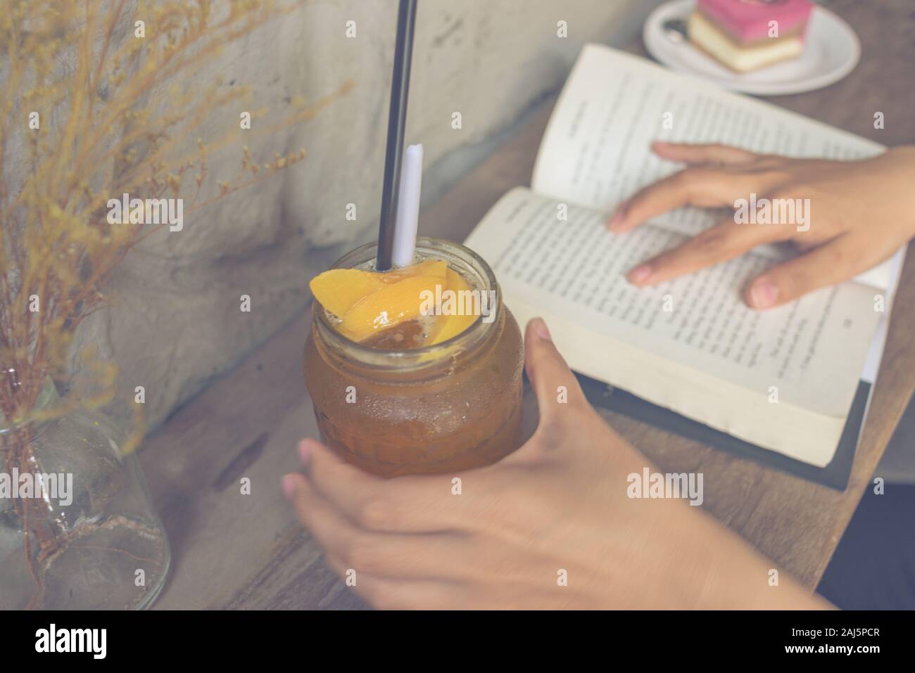 Junge Mädchen trinken Pfirsich Tee und lesen Buch Stockfoto