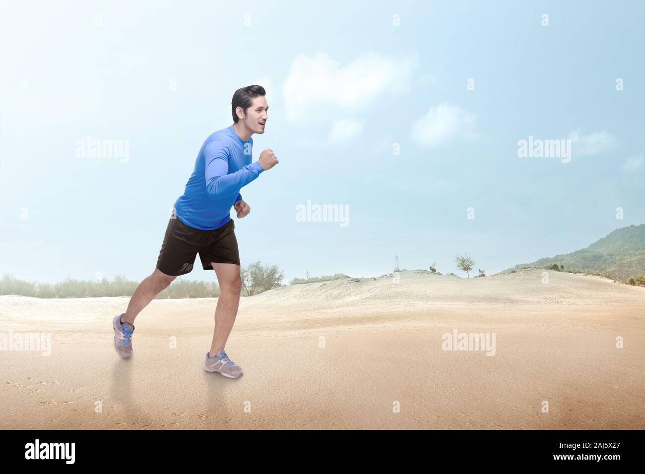 Asiatische runner Mann laufen auf der Wüste mit einem blauen Himmel Hintergrund Stockfoto