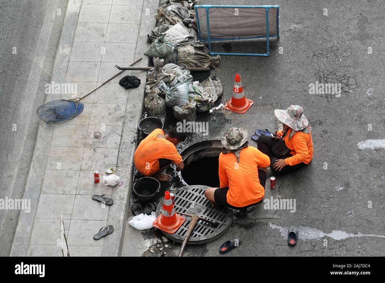 Bangkok, Thailand - 21. Dezember 2019: Arbeitnehmer Reinigung Kanalisation mit Eimer und Schaufel Säcke zu verschwenden. Stockfoto