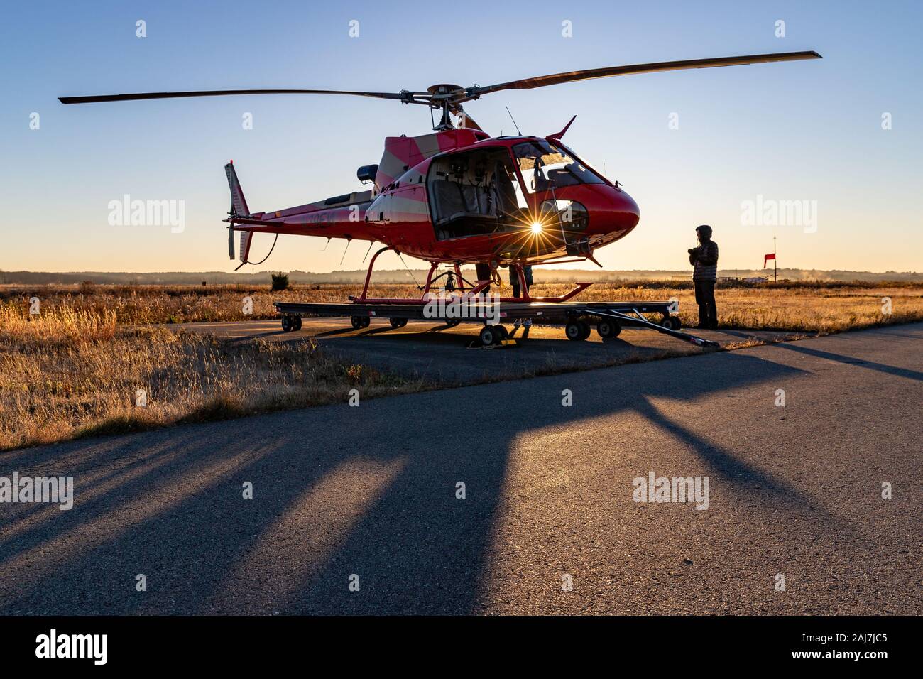 Mann, der an Bord des Hubschraubers geht und das Licht des Sonnenaufgangs durchscheint. Stockfoto