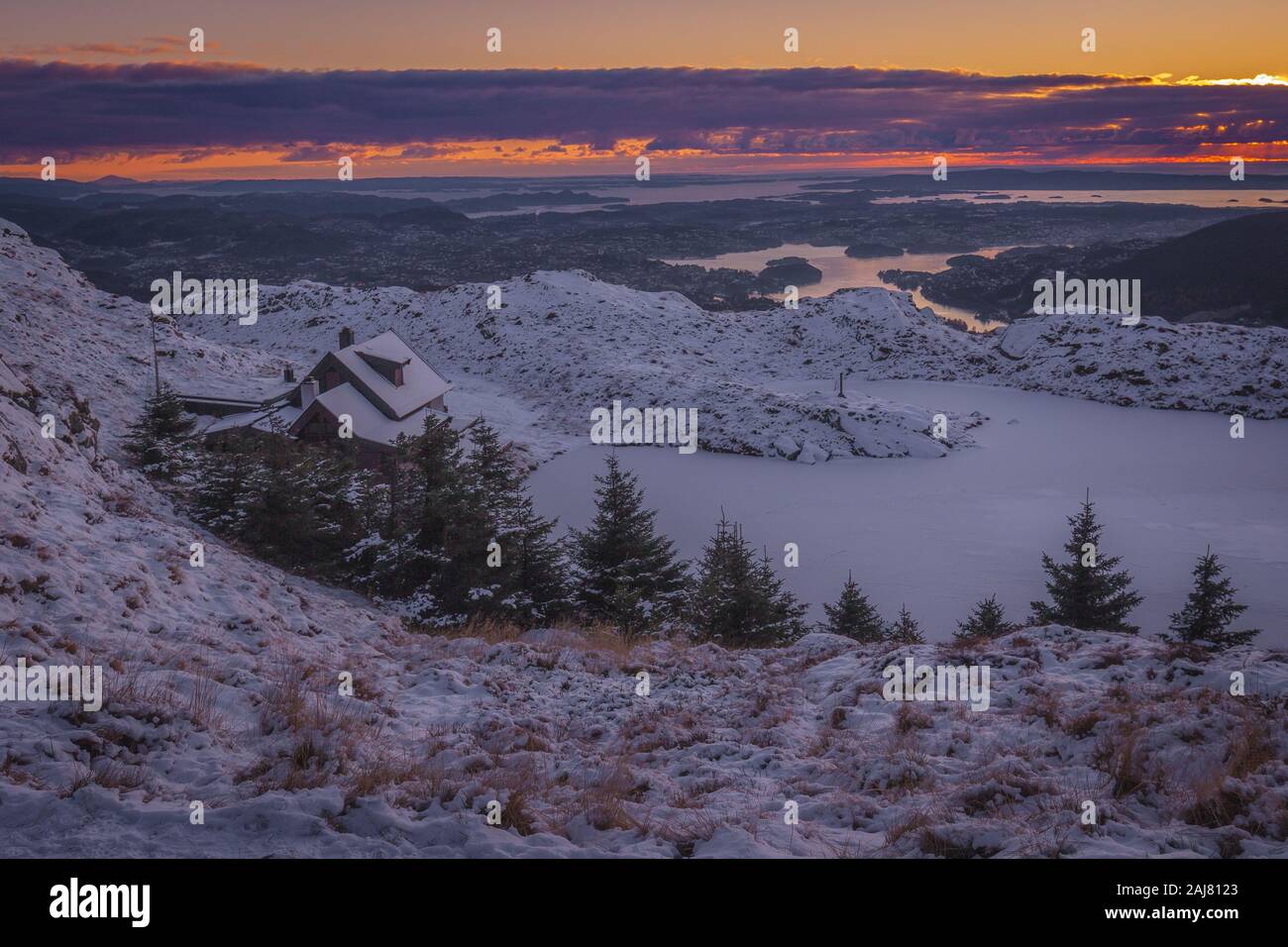 Mount Ulriken, Bergen, Norwegen - 2019.11.09. Haus bedeckt mit Schnee an der Oberseite des Ulriken Berg. Gefrorenen See und Sonnenuntergang Panorama der Nördlichen fjor Stockfoto
