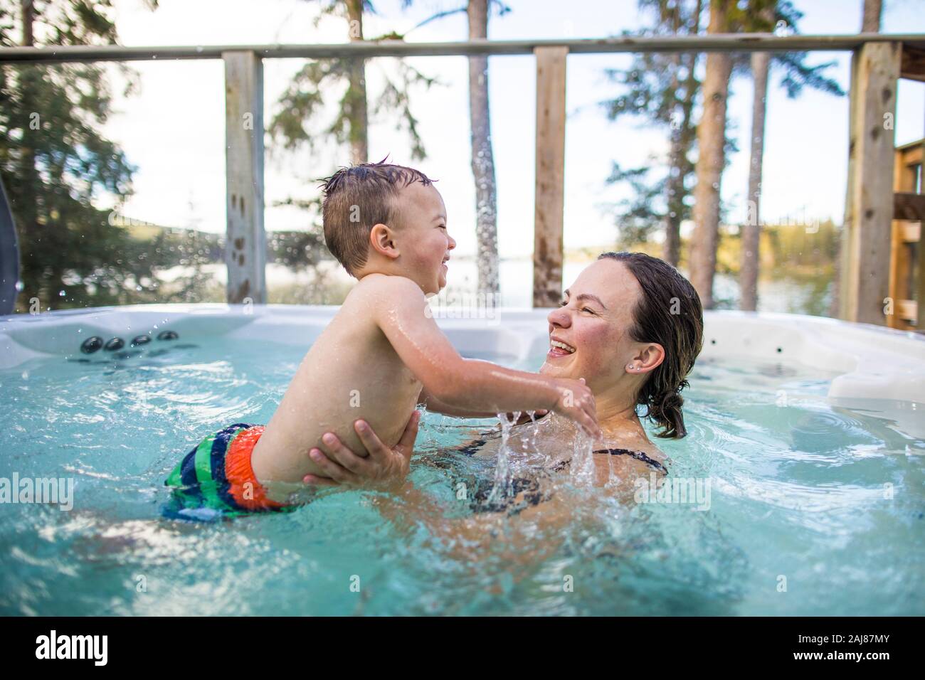 Kleiner Junge planschend und spielend mit Mutter im Schwimmbad Stockfoto