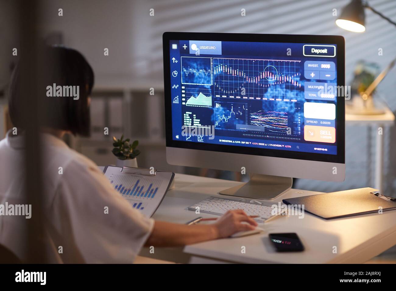 Ansicht der Rückseite des Geschäftsfrau mit dunklen kurzen Haaren Analyse der Tabellen auf den Computer im Büro Stockfoto