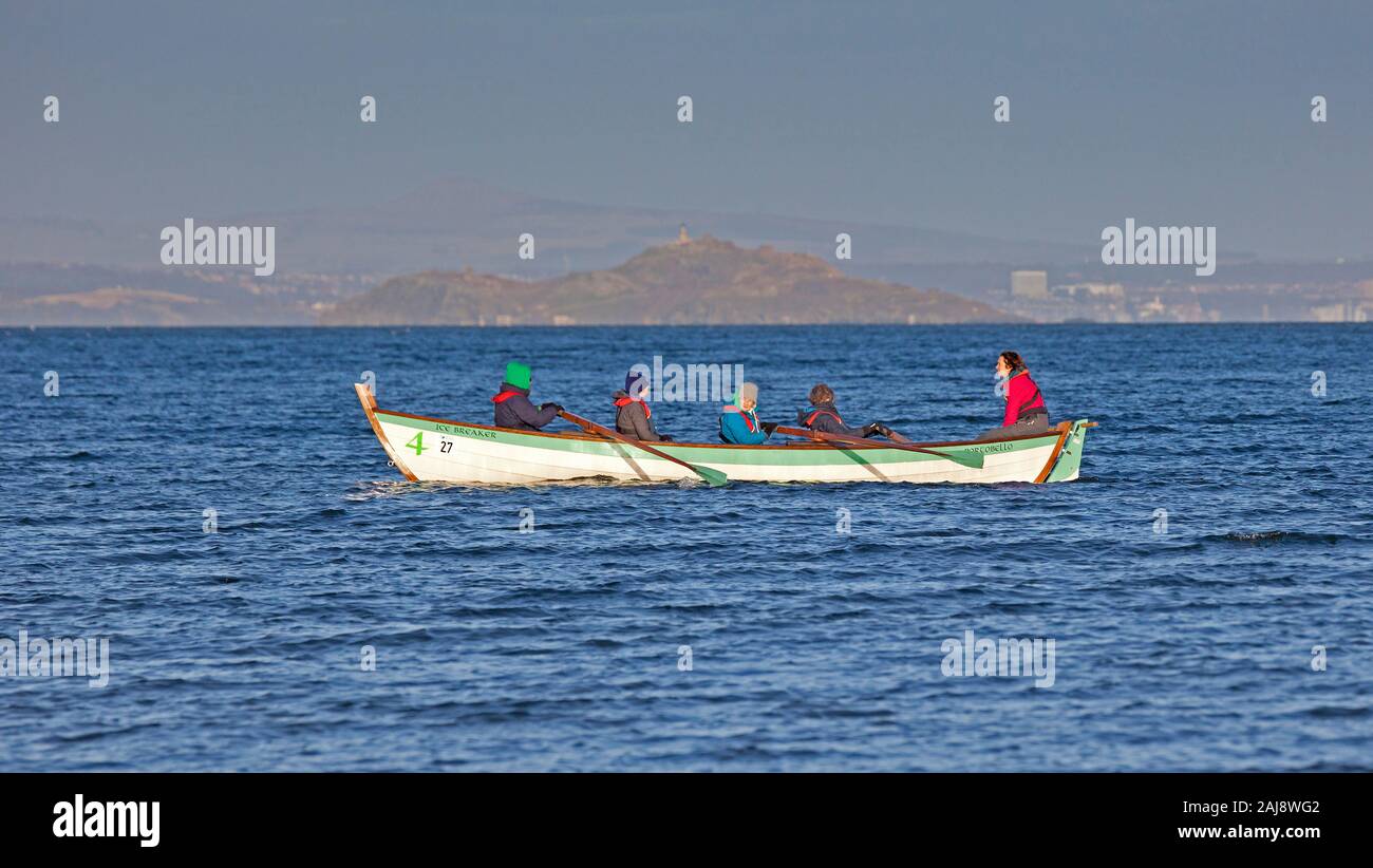 Portobello, Edinburgh, Schottland, Großbritannien. 3. Januar 2020. Wetter 6 Grad Celsius, für die kühle Brise verpackt genießen Sie die Wintersonne, immer etwas für Familien am Sandstrand wie der Portobello rudernde Mannschaft heraus mit Ihrem Boot die Ice Breaker und Leute ihre Hunde zu Fuß einige tragende Körper wärmer zu schützen Sie sich vor der Kälte zu sehen. Stockfoto