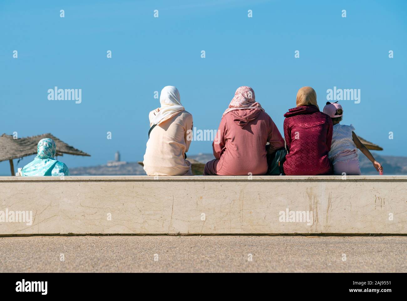 Drei Muslime Frauen sitzen auf einer niedrigen Mauer Stockfoto