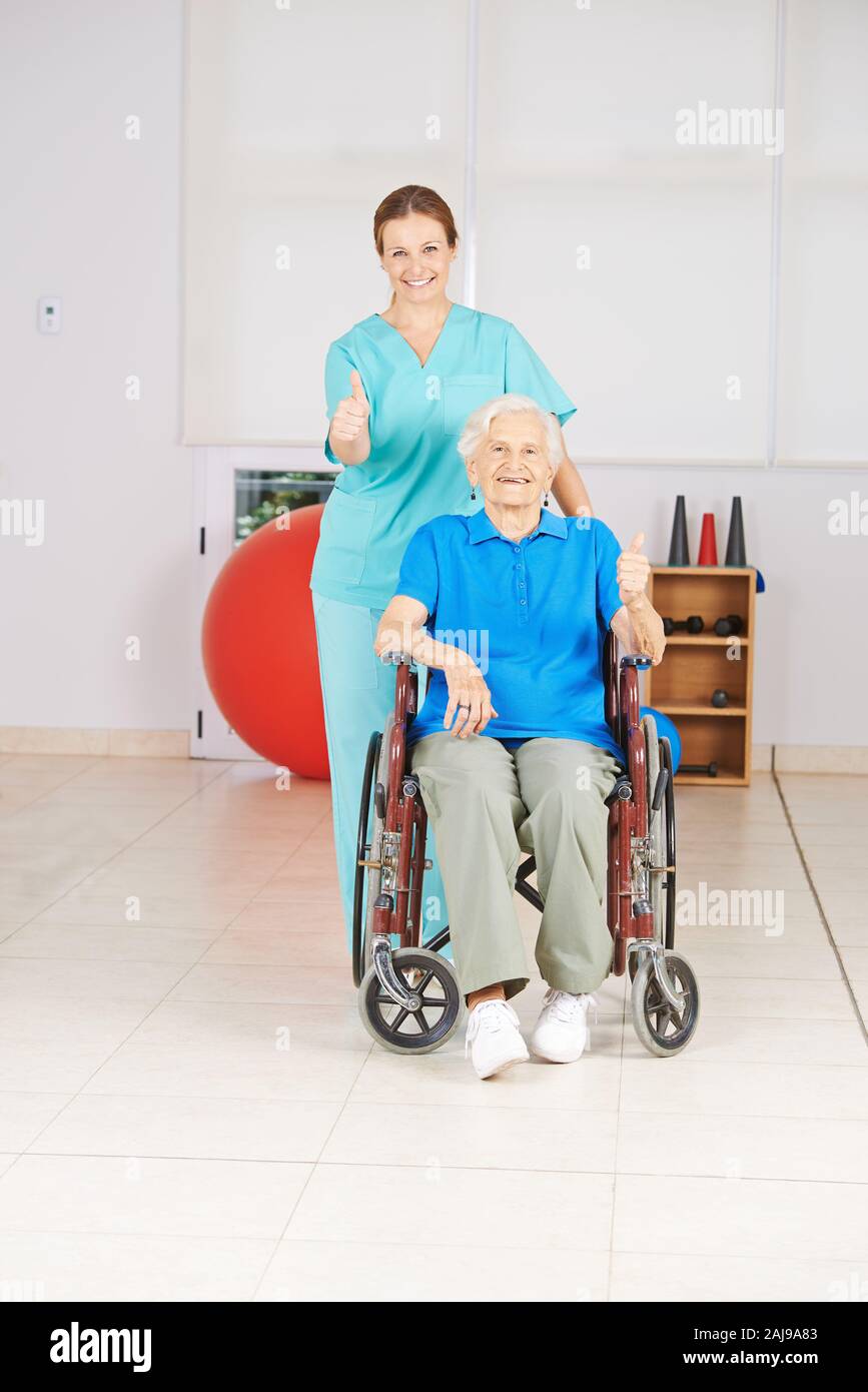 Gerne ältere Frau im Rollstuhl und Krankenschwester holding Daumen hoch Stockfoto