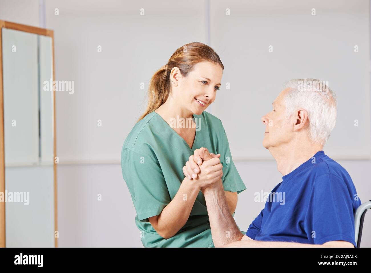 Mann im Rollstuhl Züge seine Hand mit einer Krankenschwester nach einem Schlaganfall Stockfoto