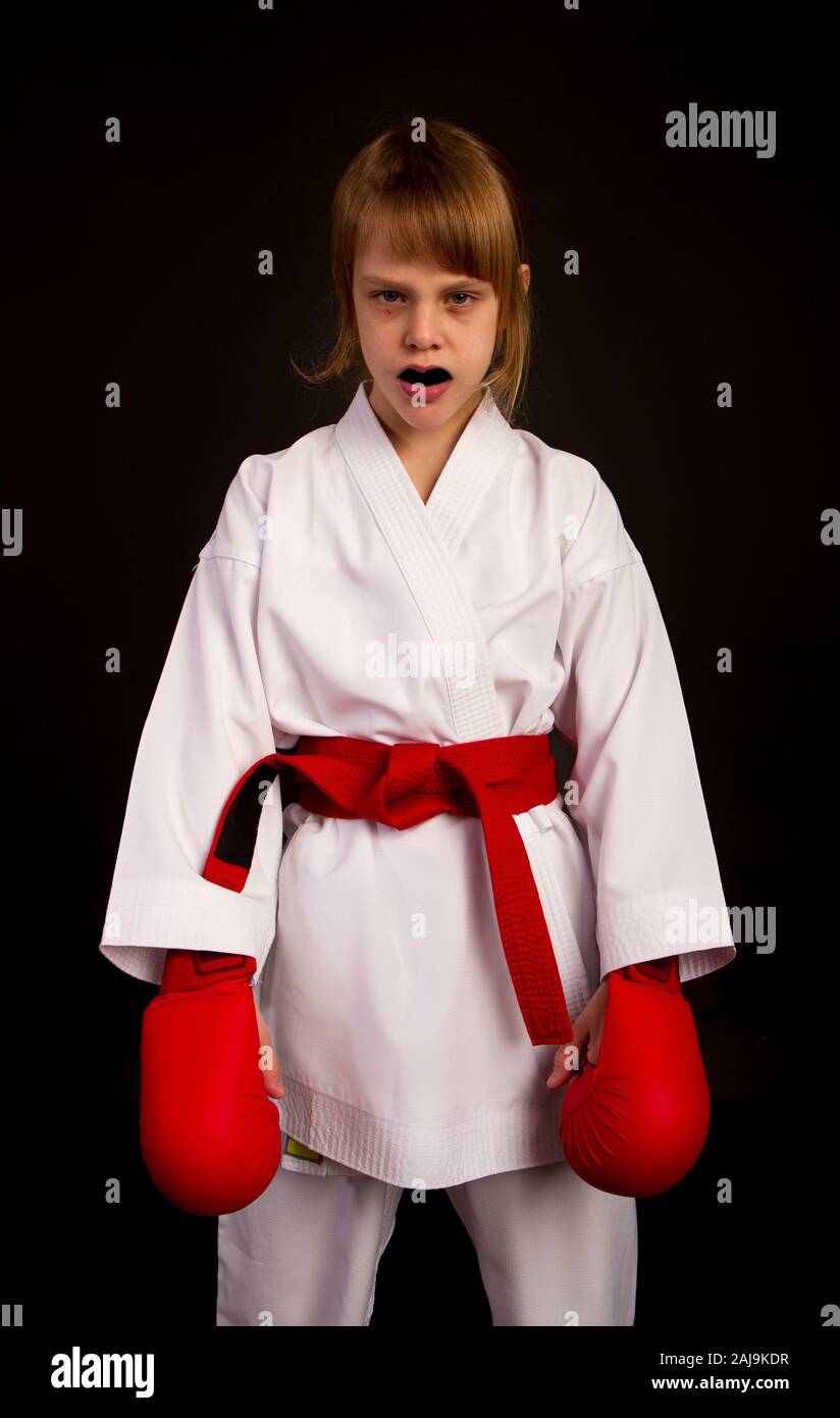 Karate Mädchen in einem weißen Kimono und roten Outfit bereitet für ein Duell auf einem dunklen Hintergrund Stockfoto