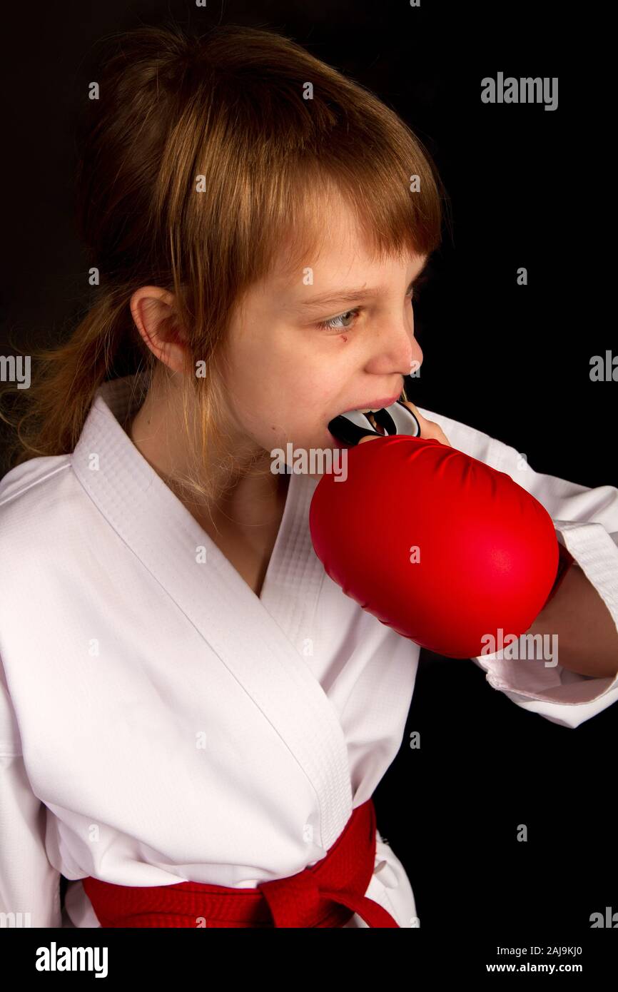 Karate Mädchen in einem weißen Kimono und roten Outfit Vorbereitung für einen Kampf, und stellt in seinem Mund eine schützende Mundstück Stockfoto