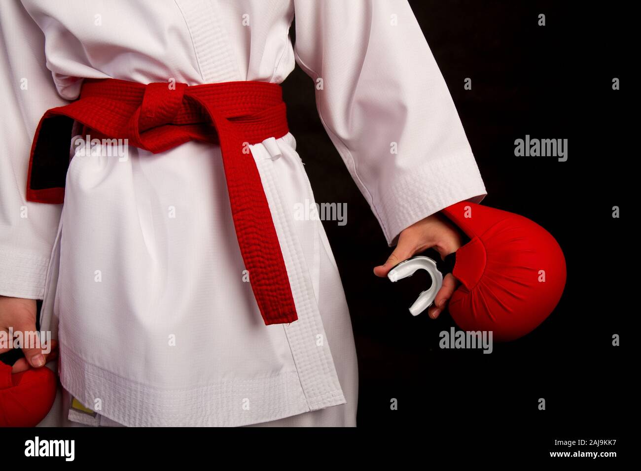 Karate Mädchen in einem weißen Kimono und ein rotes Outfit bereitet für ein Duell und hält eine capcarate Mädchen in einem weißen Kimono und ein rotes Outfit bereitet sich auf ein Duell ein Stockfoto