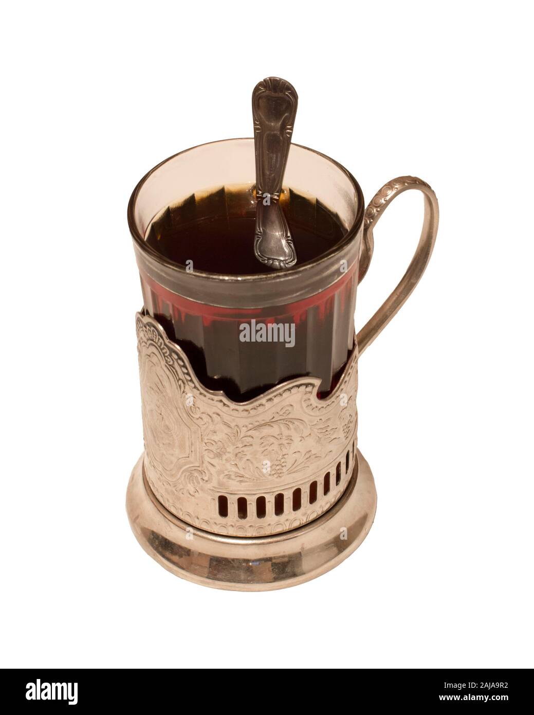 Ein Glas heißen Tees in einem Glasbecher, in einem Getränkehalter und einem Löffel in einem Glas. Spiegelung eines Löffels in Wasser. Stockfoto