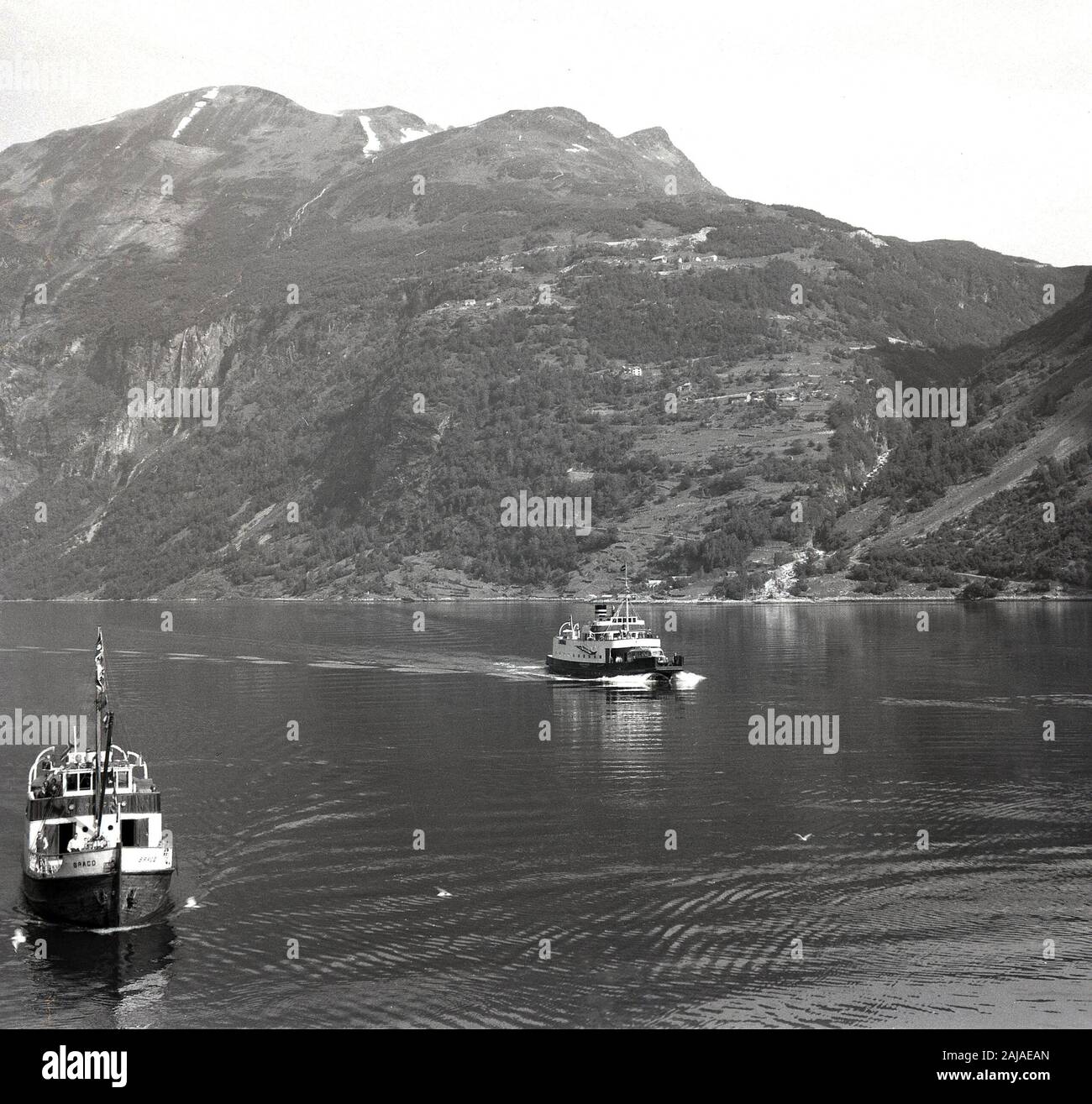 1950er Jahre, historische Autofähren in einem Fjord, Norwegen. Die Zuflüsse der norwegischen Fjorde mit ihren tiefen Gewässern und dem steilen Land auf drei Seiten sind das Ergebnis vergletscherter Täler. Stockfoto