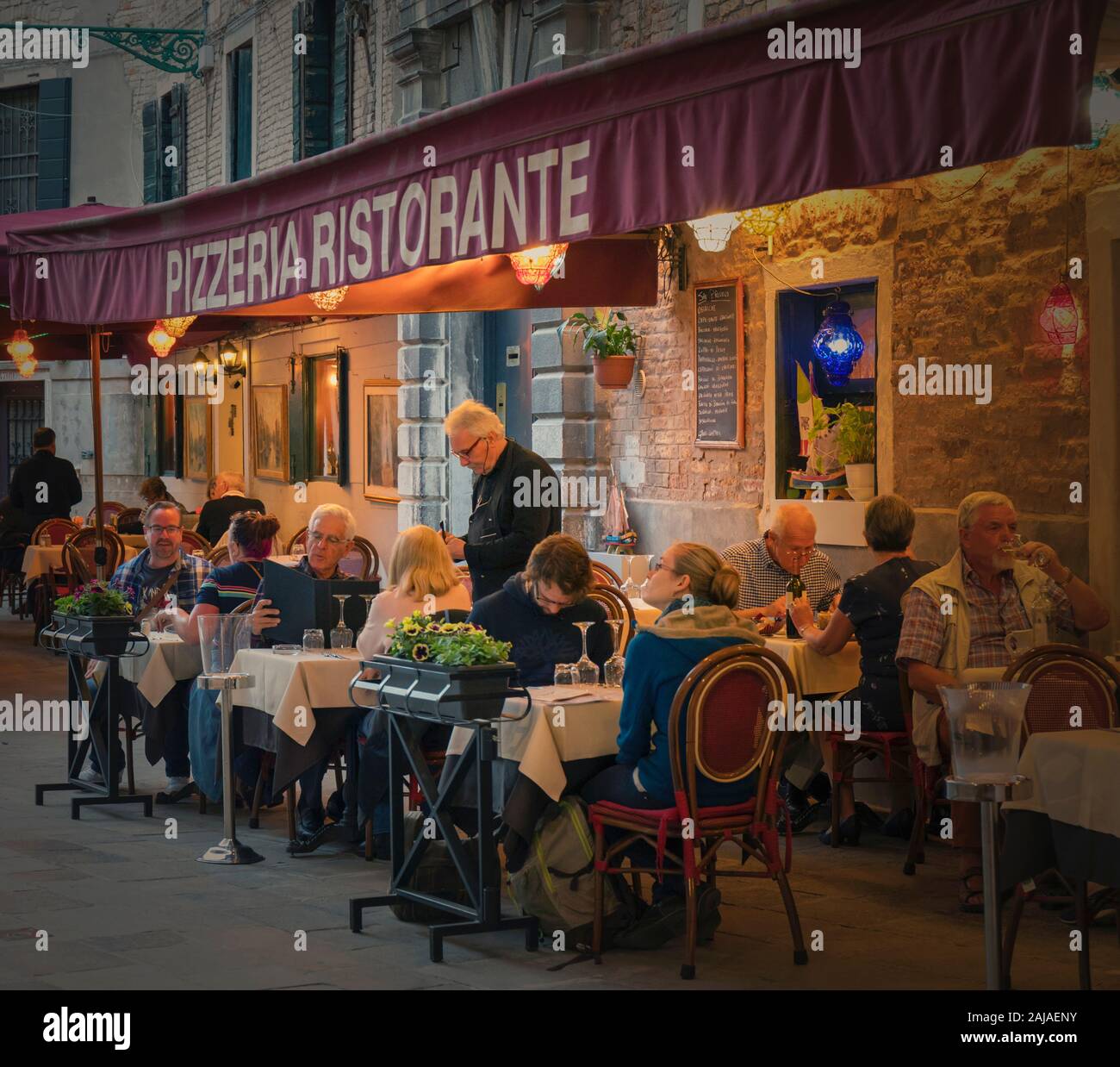 Kellner die Bestellung von Diners auf der Restaurant Terrasse neben dem Rio di San Provoio, Venedig, Provinz Venedig, Region Venetien, Italien. Venedig ist ein Uneso Stockfoto