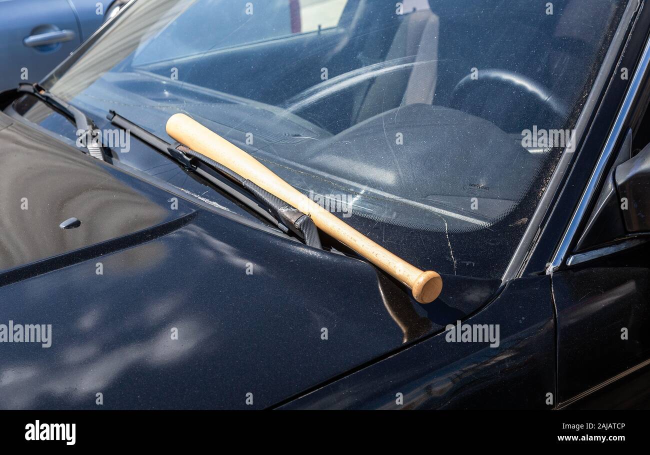 Holz- Baseballschläger liegt am schwarzen Auto Stockfoto