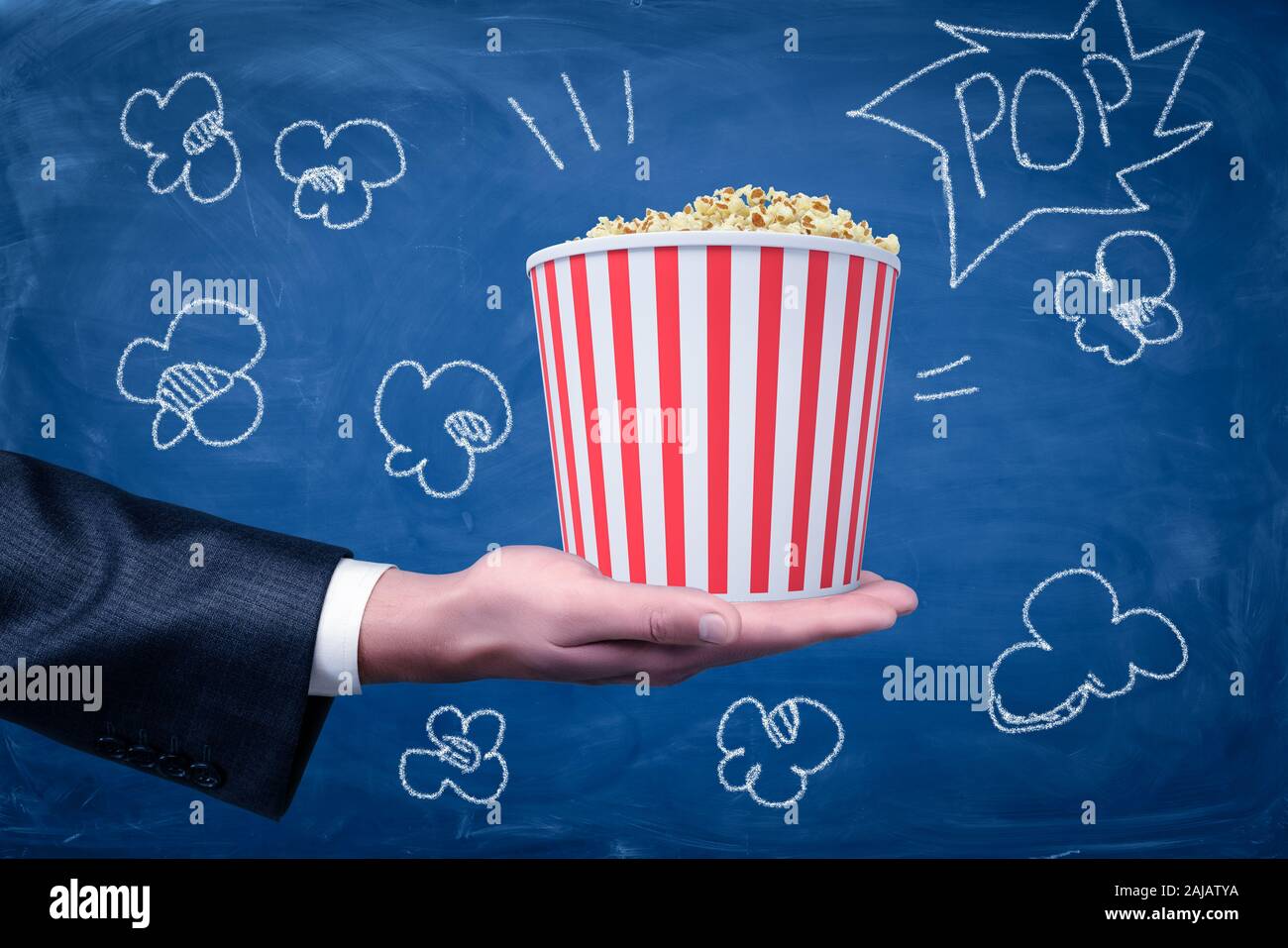 Männliche hand Popcornwanne auf blauem Hintergrund. Filmproduktion Industrie. Film zu machen. Cineastische Kunst. Stockfoto