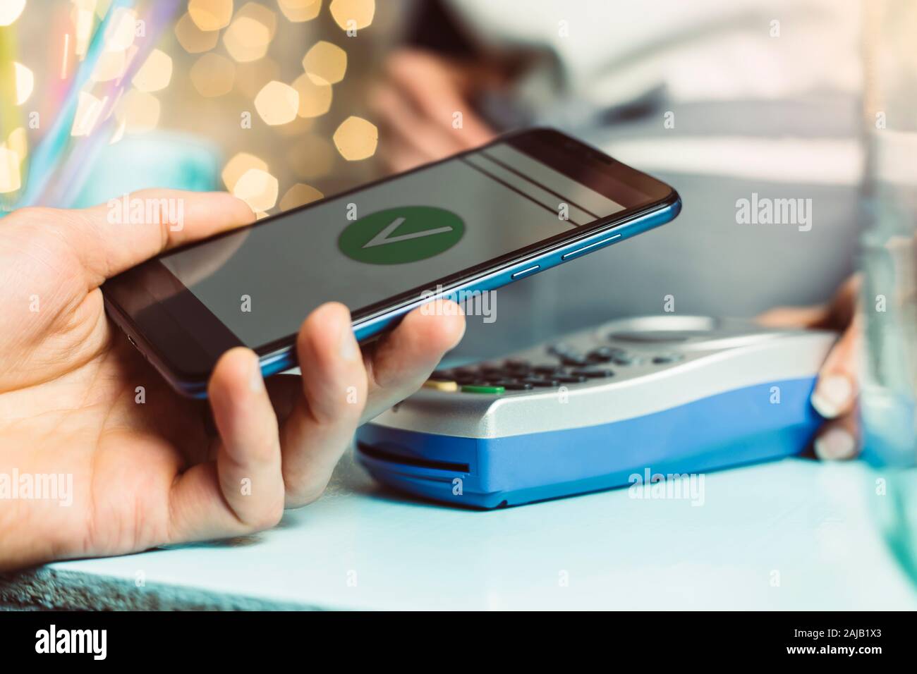 Die Hand des Kunden zahlt sich für das Smartphone im Geschäft mit NFC-Technologie aus. Handy zahlt die Rechnung mit kontaktloser Technologie. Stockfoto