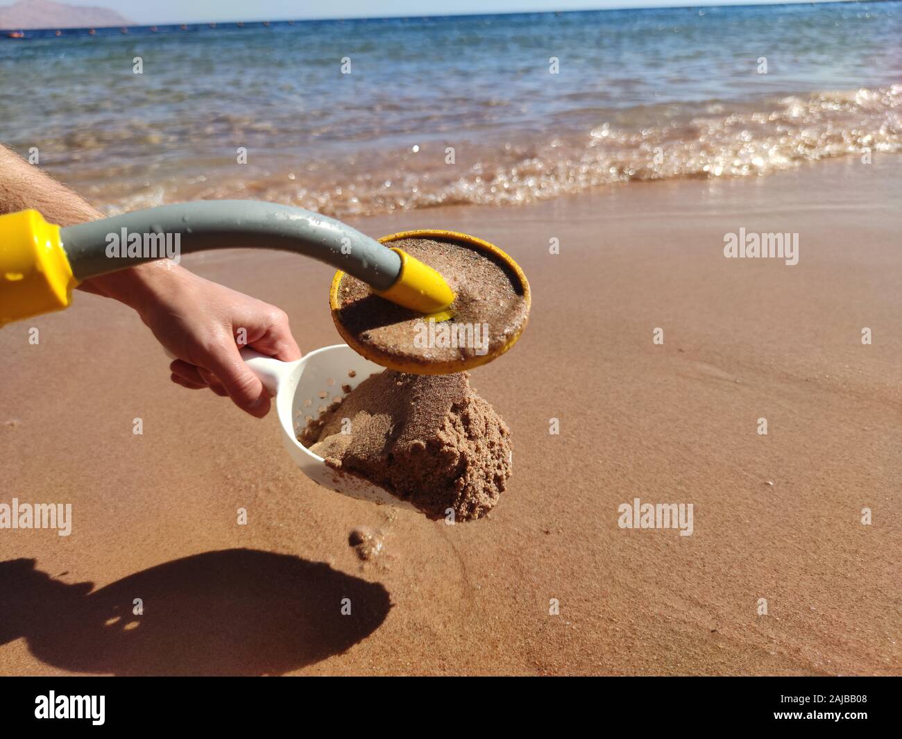 Das Foto von einem Unterwasser Metalldetektor und eine Schaufel im Sand. Schatz suchen und touristische Abenteuer Hintergrund. Stockfoto